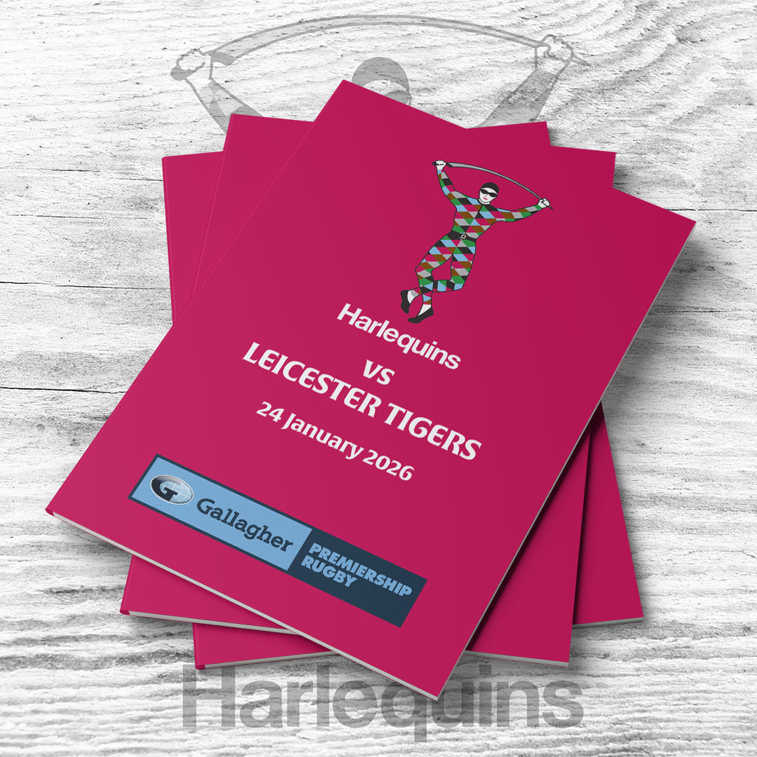 Stack of pink event programs for Harlequins vs Leicester Tigers match on a wooden surface